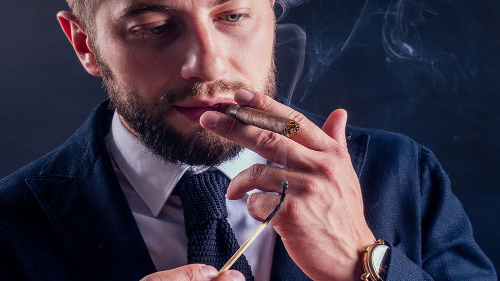 Barbat care isi aprinde si fumeaza un trabuc