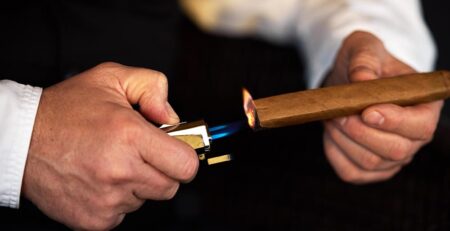 cele mai bune brichete pentru trabucuri - barbat care aprinde un trabuc cu bricheta cu arzator