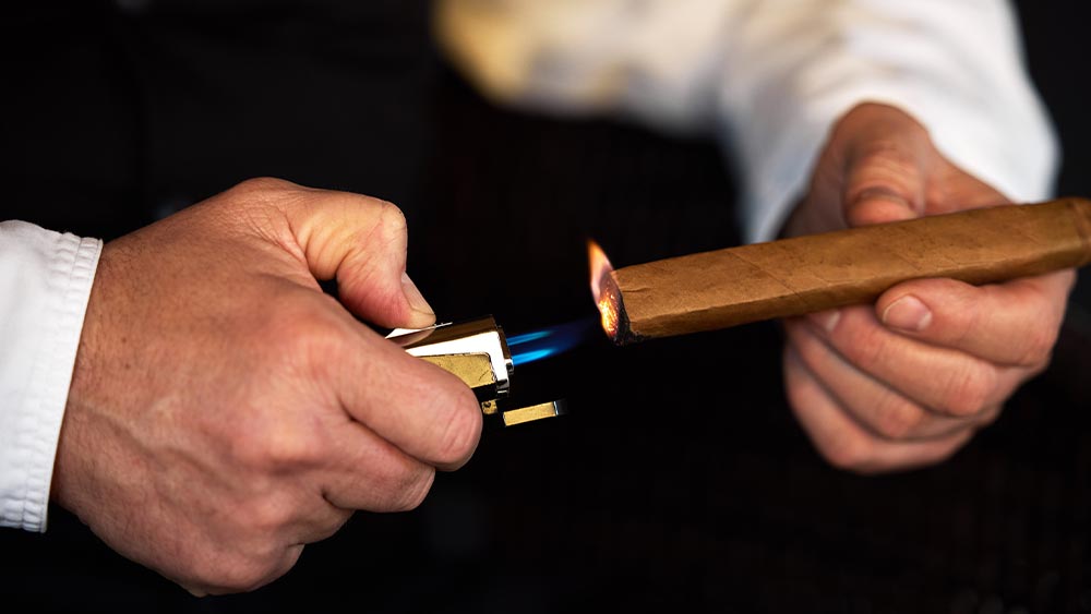 cele mai bune brichete pentru trabucuri - barbat care aprinde un trabuc cu bricheta cu arzator